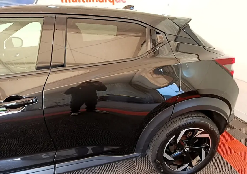 Vue latérale droite du Nissan Juke DIG-T 114 DCT noir 2022, mettant en valeur la porte arrière et la roue arrière au design moderne.