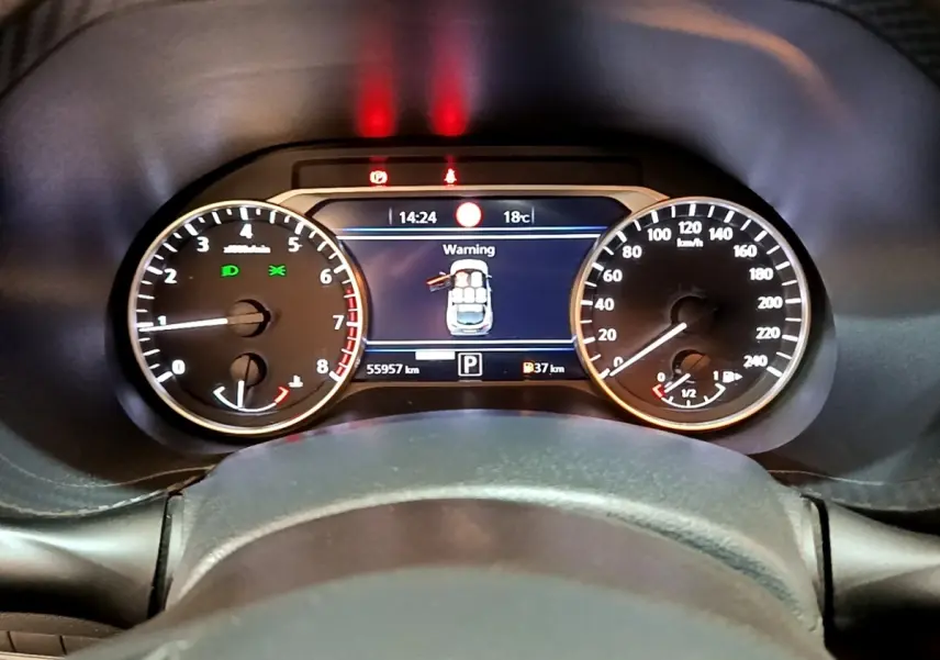 Vue rapprochée du tableau de bord numérique du Nissan Juke noir 2022, affichant une alerte de porte ouverte.