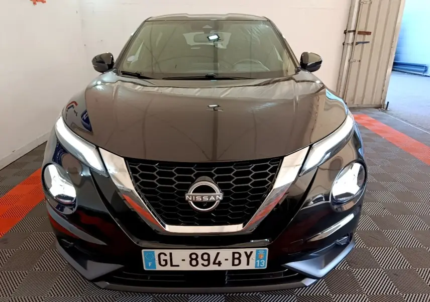 Vue avant d'un Nissan Juke noir 2022 avec calandre en V chromée et phares ronds LED allumés.