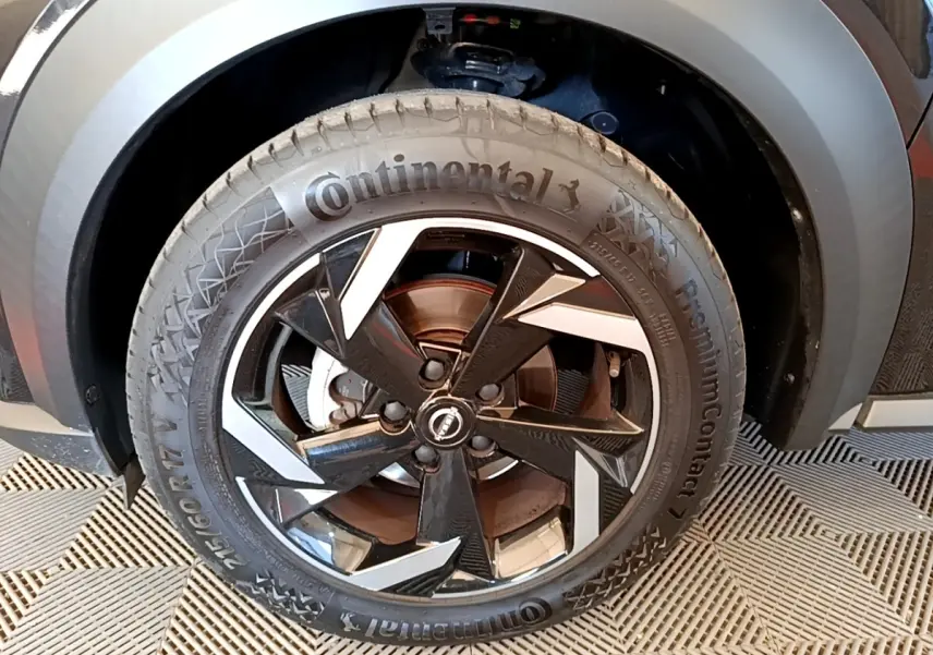 Gros plan sur la roue avant droite du Nissan Juke noir 2022 avec jante alliage bicolore et pneu Continental.