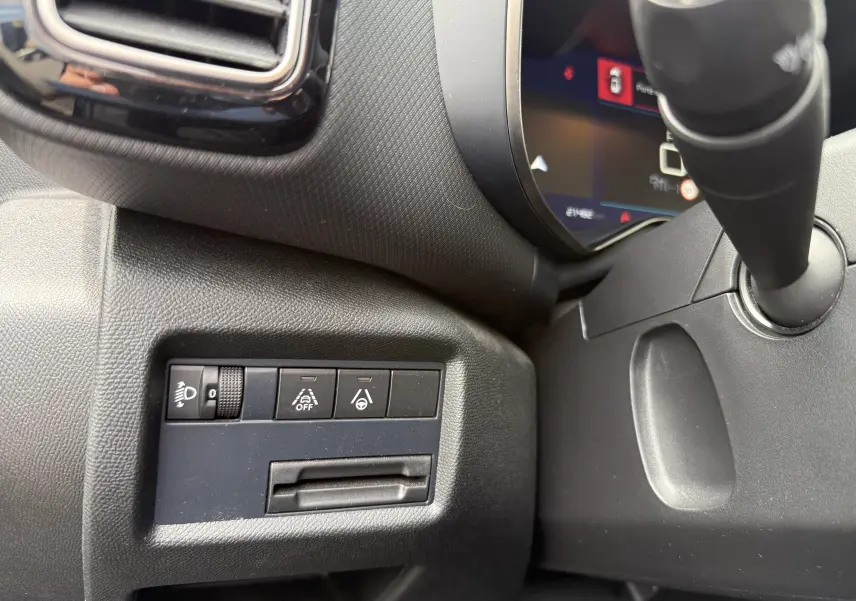 Gros plan sur les commandes de réglage des phares et aides à la conduite du tableau de bord côté gauche d’un Citroën C5 Aircross Hybrid bleu.