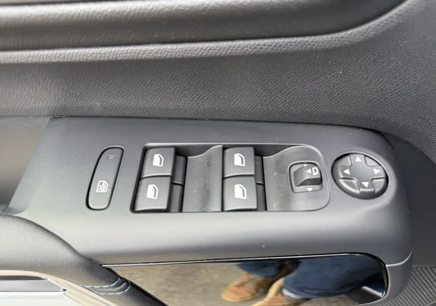 Gros plan sur les commandes de lève-vitres et rétroviseurs côté gauche intérieur du Citroën C5 Aircross Hybrid bleu foncé 2025.