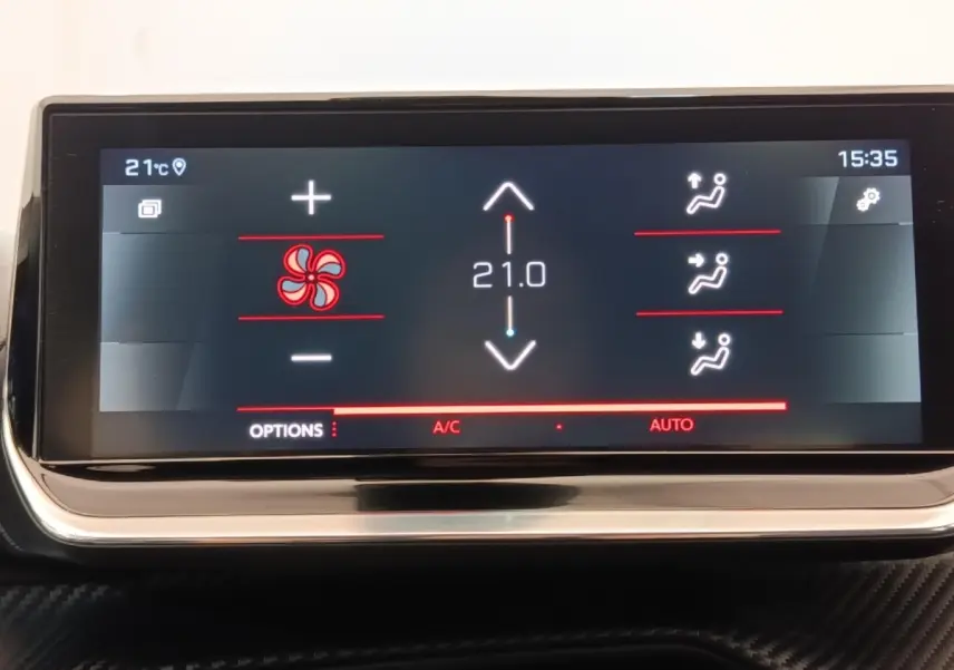 Écran tactile du tableau de bord de la Peugeot 208 blanc, affichant la climatisation à 21°C en mode automatique.