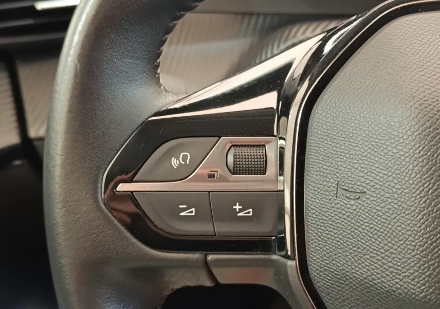 Gros plan sur les commandes gauche du volant cuir noir du Peugeot 208 PureTech 100 S&S Allure Business.