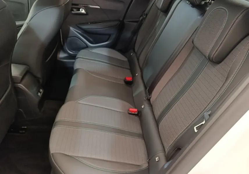 Vue intérieure côté droit montrant la banquette arrière en tissu gris et cuir noir de la Peugeot 208 blanche.