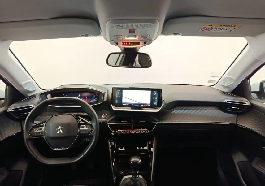 Vue intérieure avant du tableau de bord noir et volant cuir de la Peugeot 208 PureTech 100 S&S Allure Business 2021.