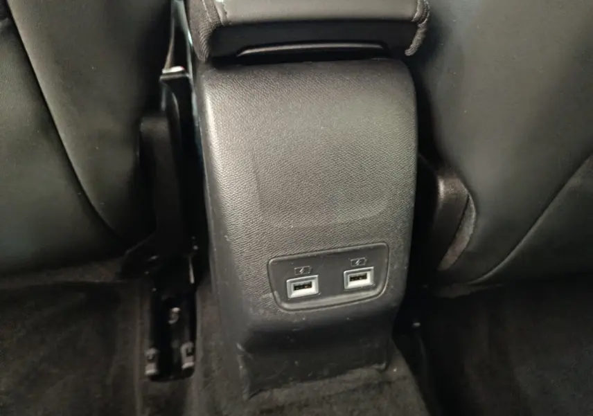 Vue rapprochée des ports USB arrière noirs situés entre les sièges avant d'une Peugeot 208 blanche.