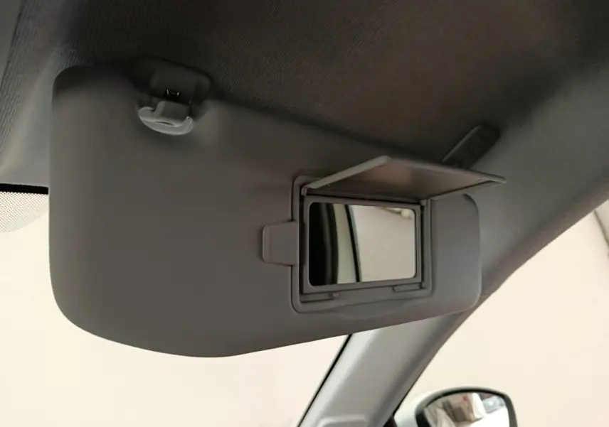 Détail intérieur du pare-soleil côté conducteur avec miroir de courtoisie ouvert dans une Peugeot 208 blanche.