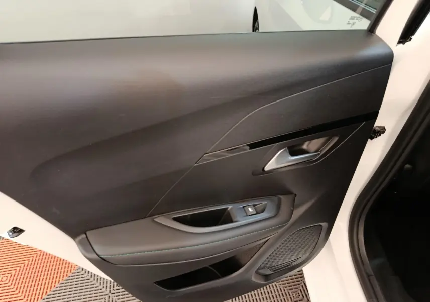 Vue rapprochée de la porte avant droite noire avec poignée argentée et commande de vitre sur Peugeot 208 blanc.