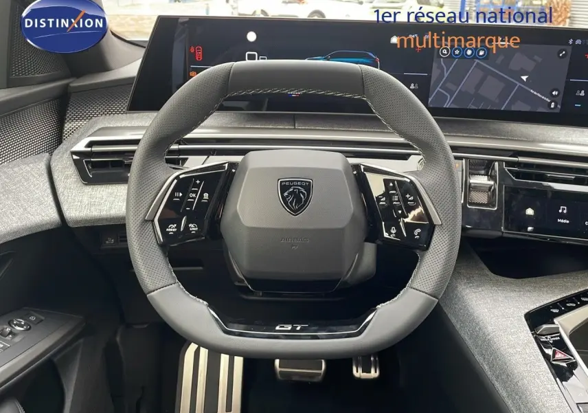 Volant GT en cuir noir perforé du Peugeot 5008 Hybrid 2025 avec tableau de bord numérique et commandes intégrées.
