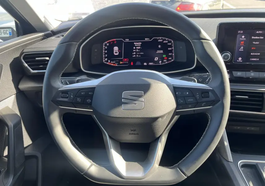 Volant cuir multifonction SEAT Leon IV 2023 vu de face, avec tableau de bord digital et écran central tactile.