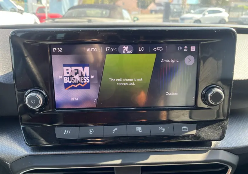 Écran central tactile du tableau de bord de la SEAT Leon IV 2023 affichant la radio BFM Business et les réglages climatiques.