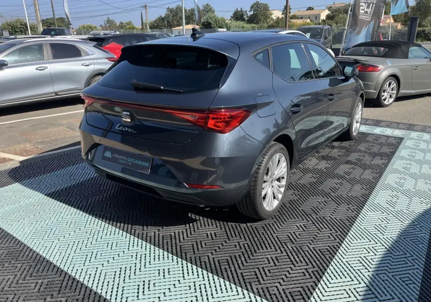 Vue 3/4 arrière droite d'une SEAT Leon IV gris magnetic metal stationnée, soulignant ses feux arrière LED et jantes alliage 17 pouces.