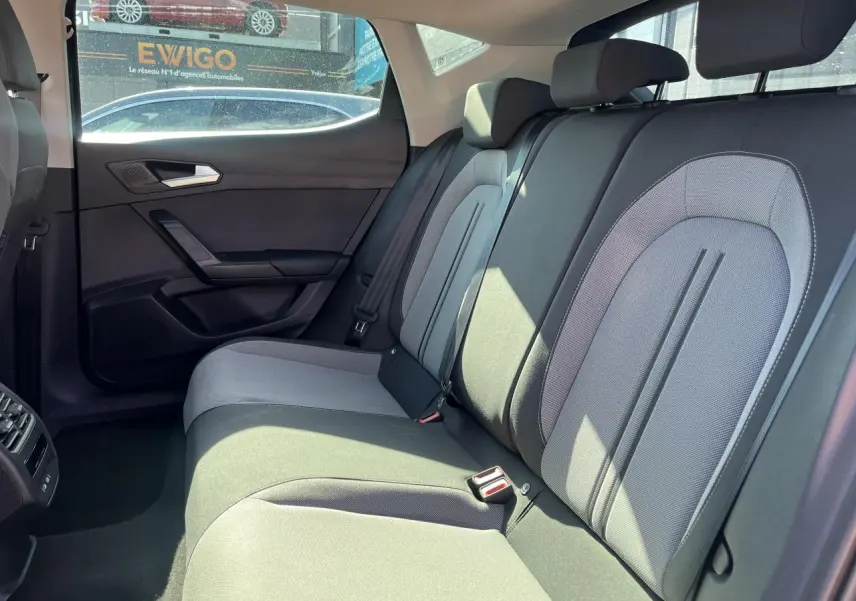 Vue intérieure sur la banquette arrière grise de la SEAT LEON IV 2023, avec appuie-têtes et ceintures visibles.