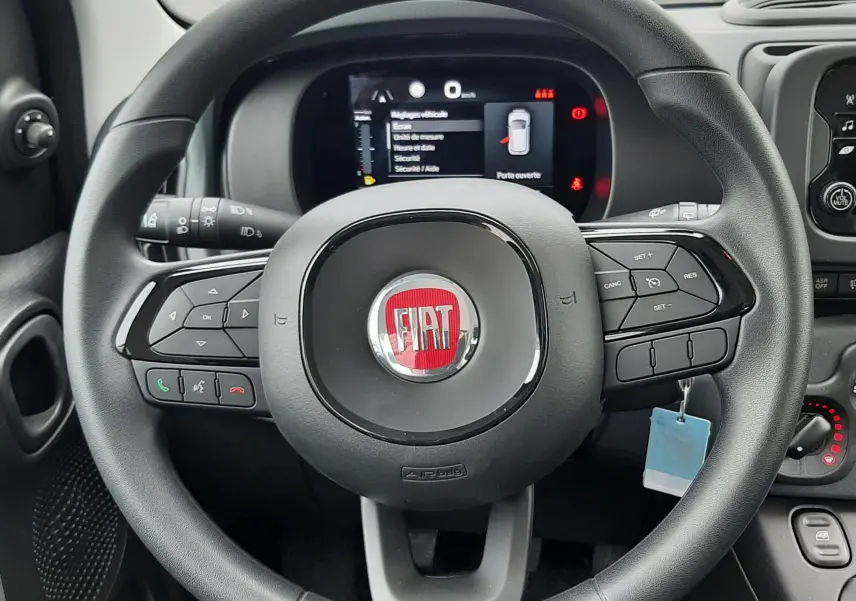 Vue rapprochée du volant noir de la Fiat Panda 2025 avec tableau de bord digital et commandes intégrées visibles.