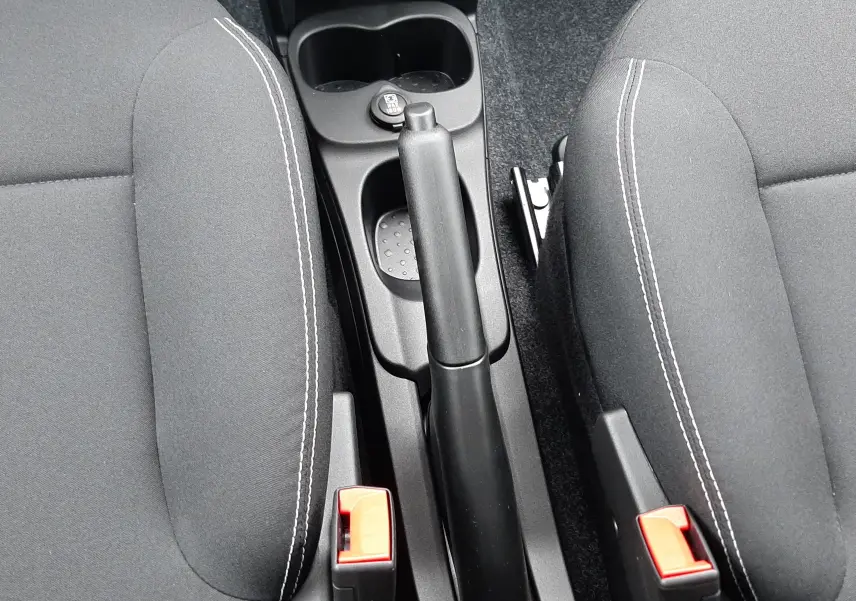 Vue plongeante sur la console centrale et les sièges noirs en tissu de la Fiat Panda 2025 blanc Gelato, frein à main manuel visible.