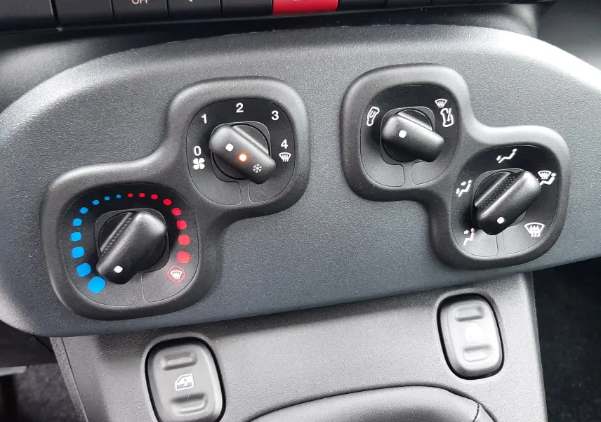 Commandes de climatisation et boutons de tableau de bord noir dans l'habitacle de la Fiat Panda 2025.
