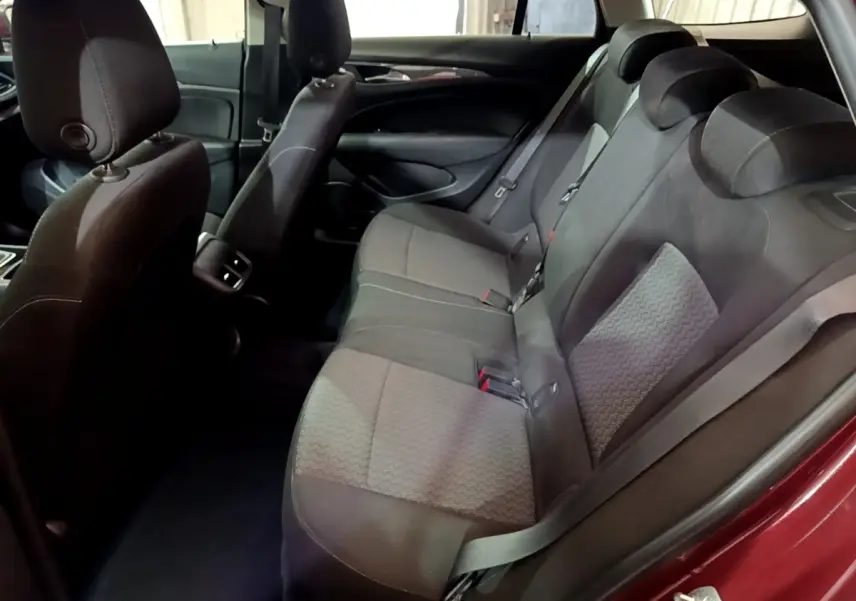 Vue intérieure côté droit sur la banquette arrière grise de l’Opel Insignia rouge, avec appuie-têtes et ceintures visibles.