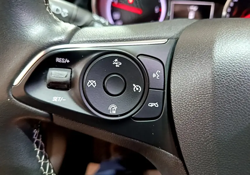 Gros plan sur les commandes de régulateur de vitesse au volant cuir noir de l’Opel Insignia rouge 2019.