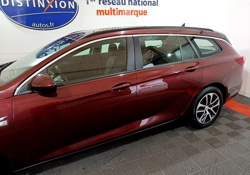 Vue de profil côté gauche d’une Opel Insignia rouge 2019 en version break, avec jantes alliage et rétroviseur assorti.