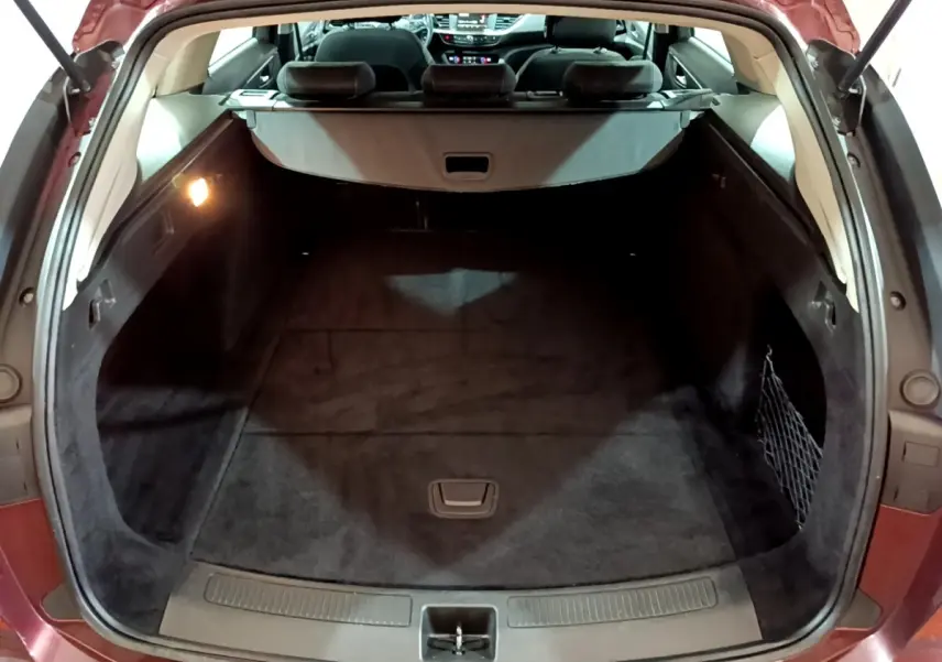 Vue arrière du coffre ouvert de l’Opel Insignia rouge, montrant un espace de chargement spacieux et propre.