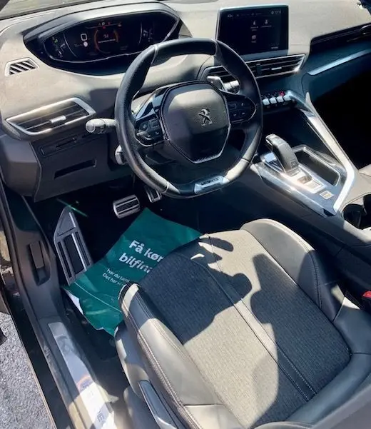 Intérieur du Peugeot 3008 2018 noir, vue côté conducteur sur le volant, tableau de bord numérique et console centrale moderne.