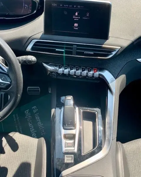 Vue intérieure centrée sur la console centrale et écran tactile du Peugeot 3008 noir, version GT Line 2018.