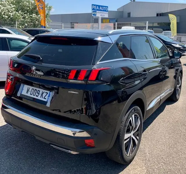 Vue 3/4 arrière droite d'un Peugeot 3008 noir de 2018 avec feux arrière à griffes et jantes alliage distinctives.