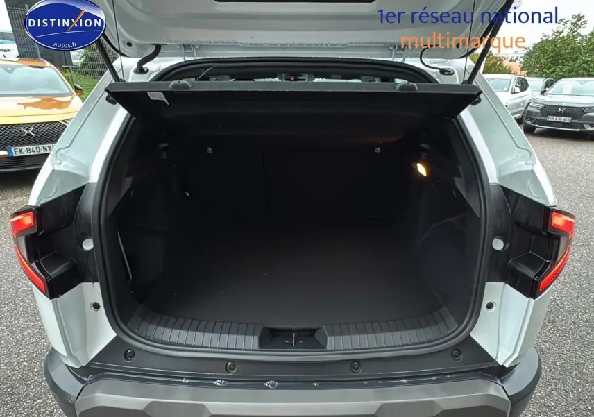 Coffre ouvert vu de l'arrière d'un Dacia Duster blanc Arctic 2025 avec feux arrière LED allumés.