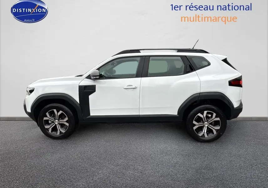 Profil droit du Dacia Duster blanc arctic 2025 avec jantes alu et barres de toit noires visibles.