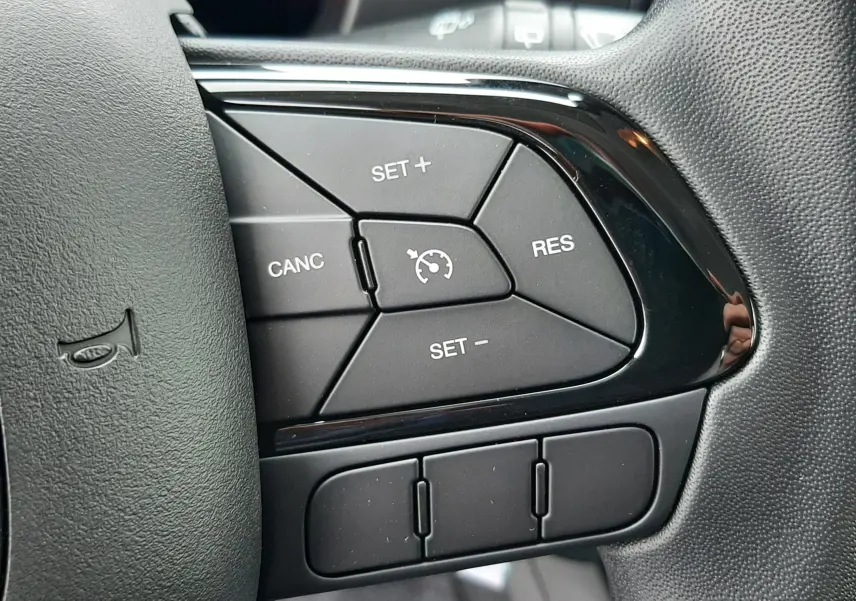 Gros plan sur les commandes de régulateur de vitesse au volant à droite de la Fiat Panda 2025, intérieur noir.