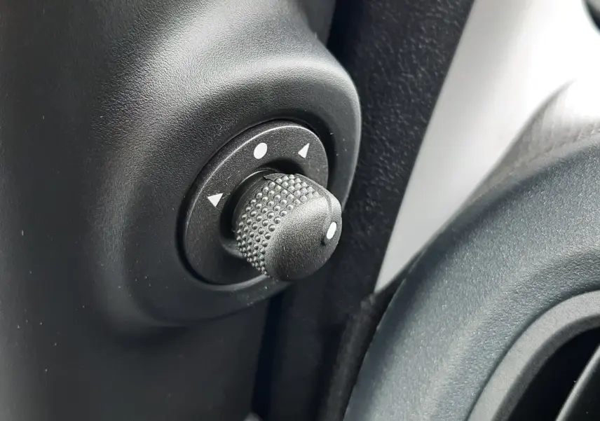 Gros plan sur le bouton de réglage des rétroviseurs intérieurs noirs de la Fiat Panda Bleu Italia 2025.