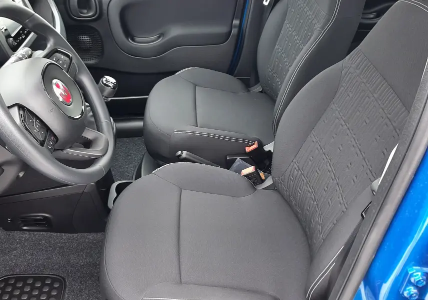 Intérieur côté conducteur de la Fiat Panda 1.0 70CH bleu Italia 2025, sièges tissu noir avec volant multifonction.