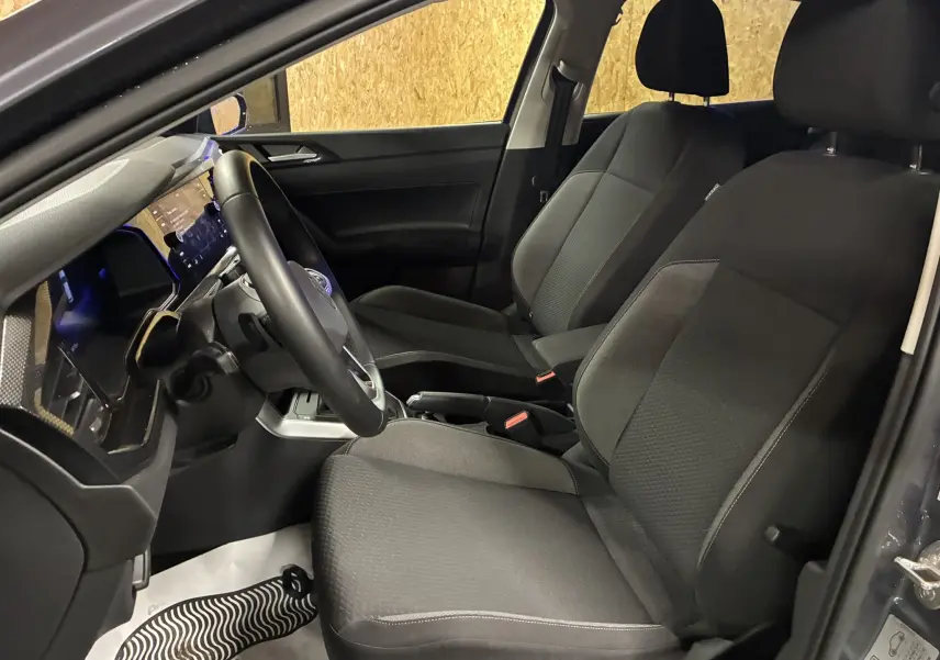 Intérieur noir de la Volkswagen Polo VI 2025, vue côté gauche sur les sièges avant et le volant.