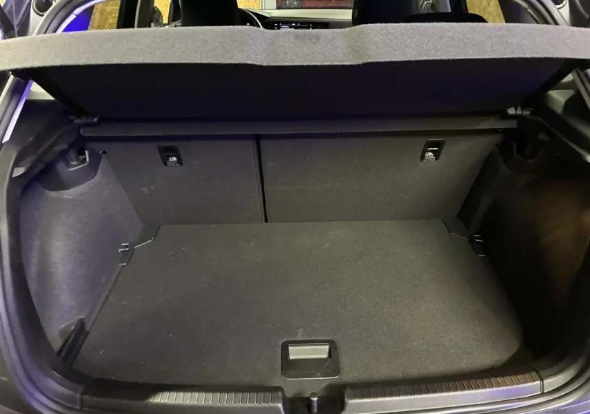 Coffre ouvert d'une Volkswagen Polo gris, vue de l'arrière montrant l'espace de chargement et la tablette cache-bagages.