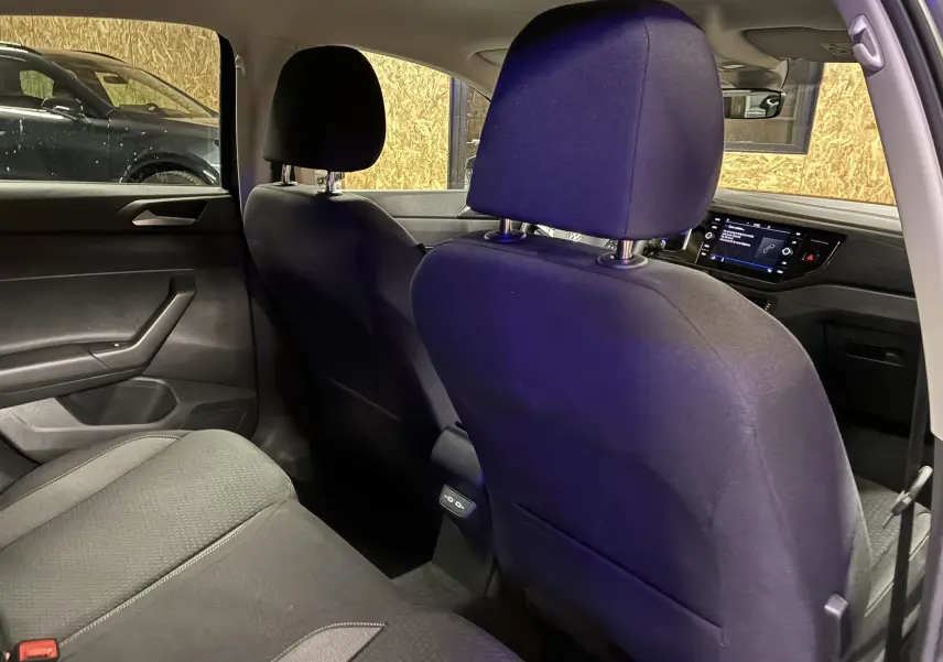 Vue intérieure arrière de la Volkswagen Polo gris 2025, montrant les sièges en tissu noir et le tableau de bord avec écran tactile.