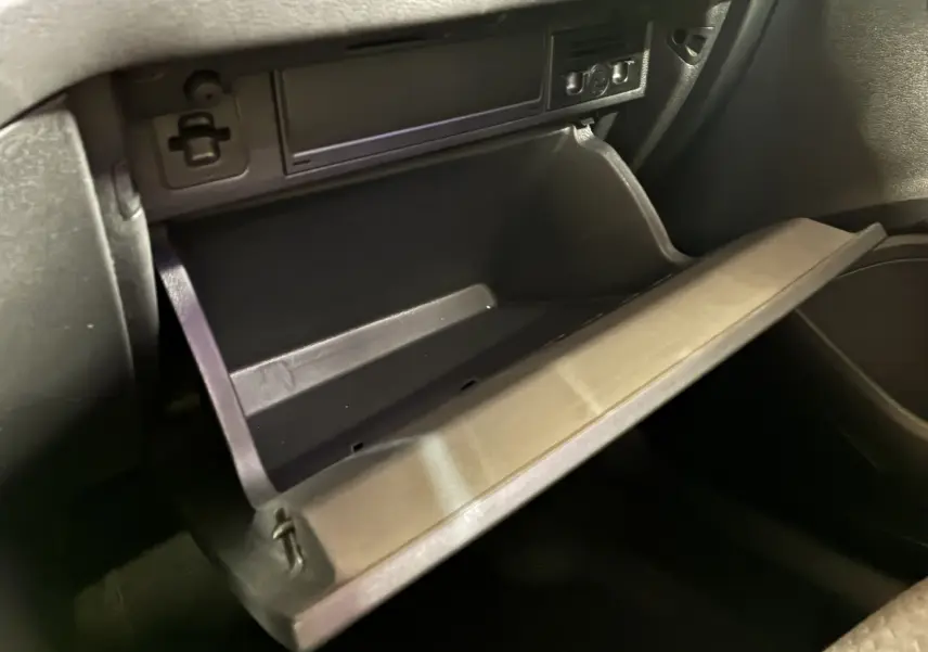 Gros plan sur la boîte à gants ouverte de la Volkswagen Polo gris, montrant l'intérieur en plastique noir.