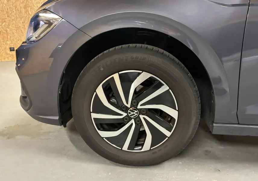 Gros plan sur la roue avant gauche d'une Volkswagen Polo gris métallisé avec jante biton stylisée.