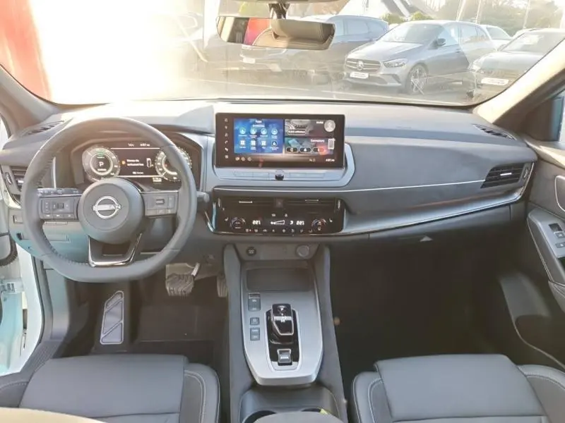 Vue intérieure avant du Nissan Qashqai Hybrid e-POWER 2025 avec tableau de bord moderne et écran tactile central.