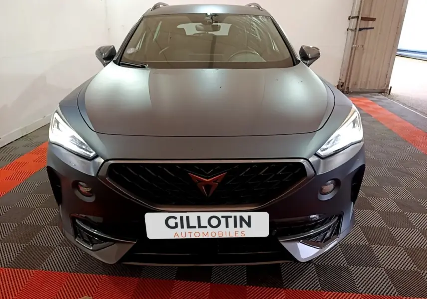 Vue avant d'une CUPRA Formentor gris foncé avec calandre noire et phares LED allumés dans un garage.