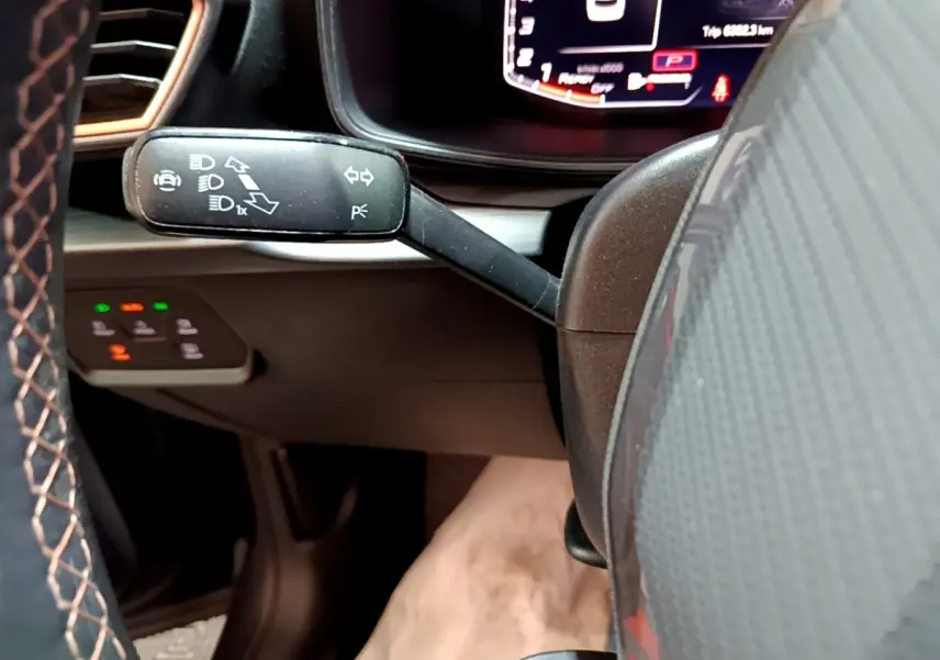 Gros plan sur le commodo gauche du volant en cuir et alu du CUPRA Formentor gris foncé, avec tableau de bord numérique en arrière-plan.