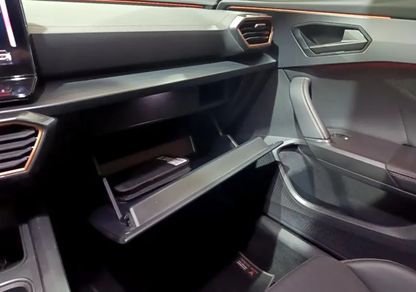 Intérieur côté passager du CUPRA Formentor gris foncé 2024, avec boîte à gants ouverte et détails en cuir et aluminium.