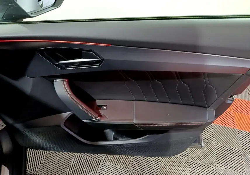 Vue rapprochée de la porte côté gauche de la CUPRA Formentor 2024, avec garniture noire et surpiqûres rouges.