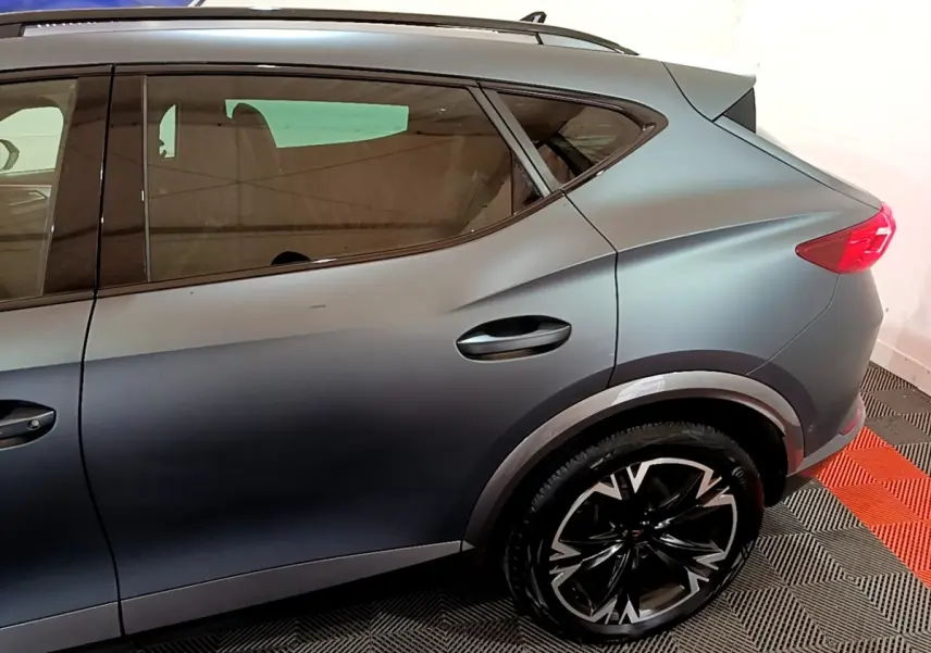 Vue latérale côté droit d'un CUPRA Formentor gris foncé 2024, mettant en valeur la roue arrière et la ligne de caisse dynamique.