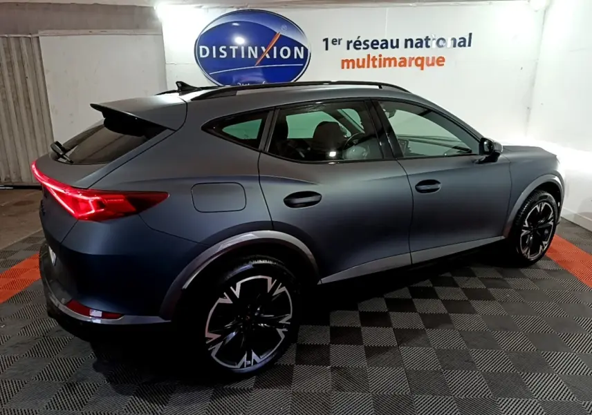 Vue 3/4 arrière droite d'un CUPRA Formentor gris foncé 2024 avec feux LED et jantes noires distinctives.
