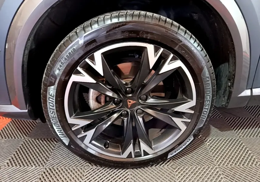 Gros plan sur la roue avant droite du CUPRA Formentor gris foncé, jante alliage noire et argentée au design dynamique.