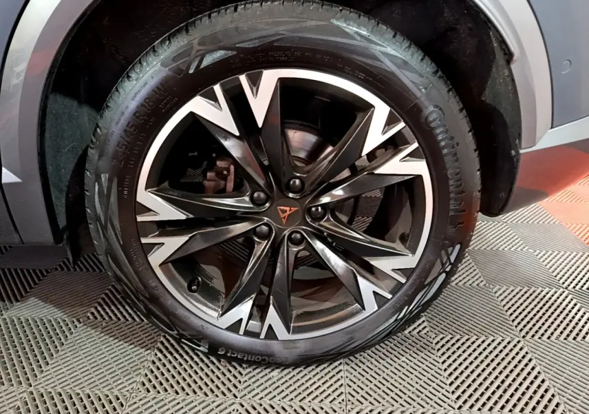 Gros plan sur la roue avant droite d'une CUPRA Formentor gris foncé avec jante alliage noire et argentée au design anguleux.