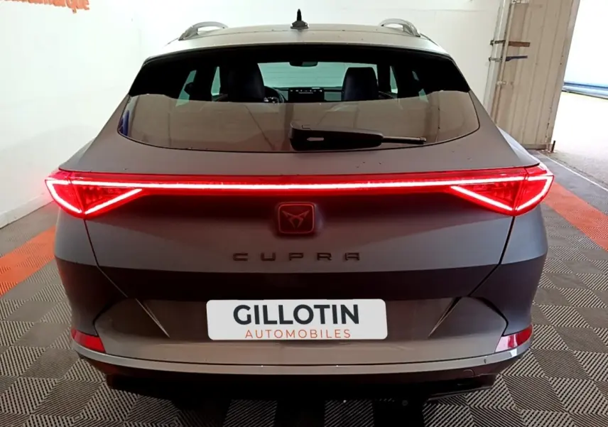 Vue arrière d'une CUPRA Formentor gris foncé 2024 avec feux LED allumés et logo central lumineux.
