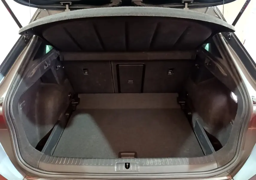 Coffre ouvert vu de l'arrière d'un CUPRA Formentor gris foncé, montrant un espace de chargement propre et spacieux.