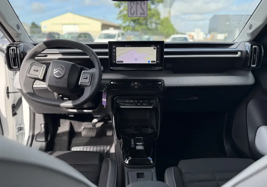Vue intérieure avant du Citroën C3 Aircross Hybrid 145, tableau de bord noir avec écran tactile central et volant multifonction.